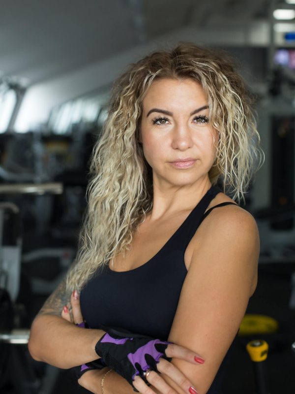 woman-with-long-blonde-curly-hair-portrait-of-a-fitness-trainer-in-the-gym.jpg